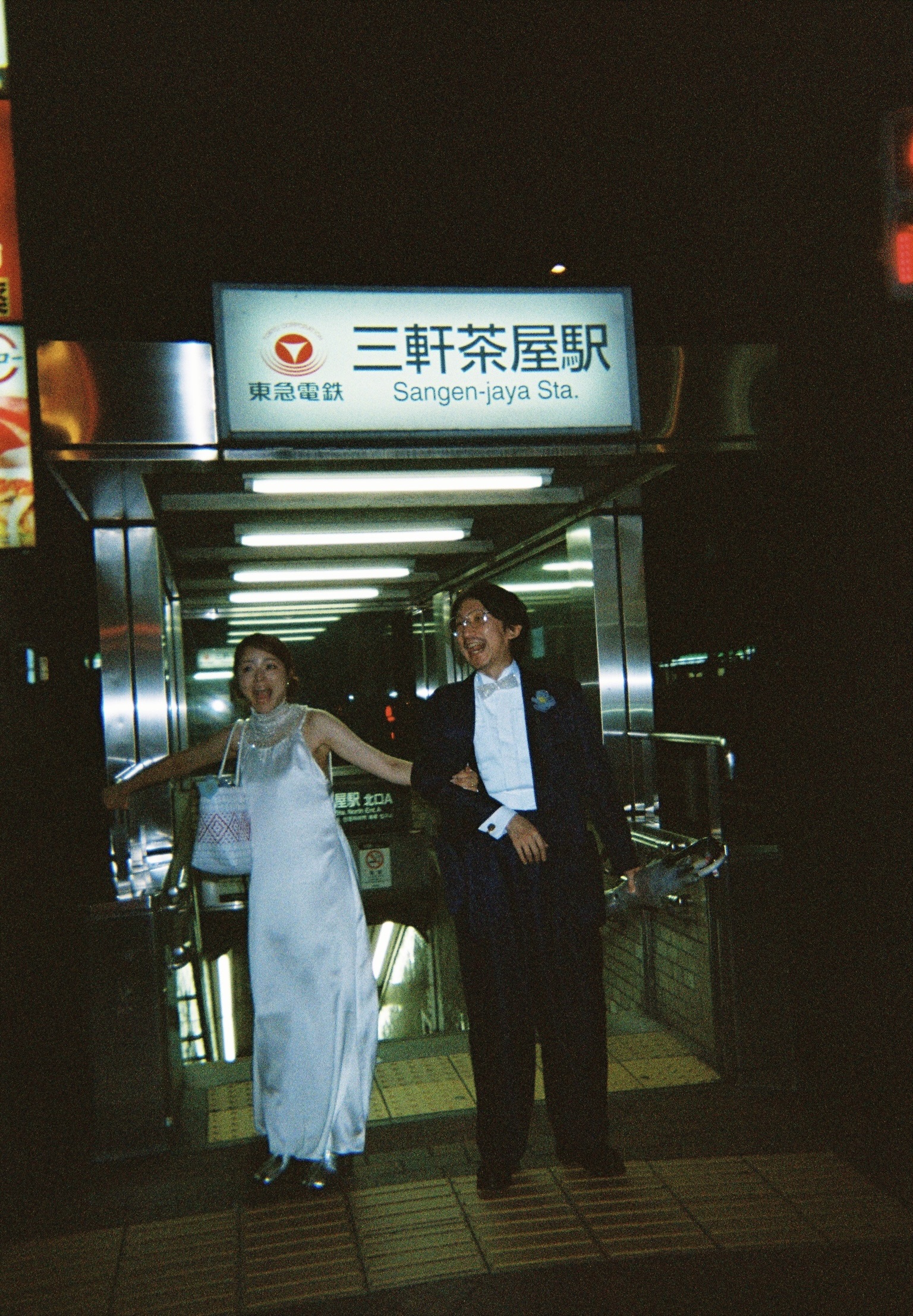 夜の三軒茶屋駅前で楽しそうに並ぶAtsushiとWakako